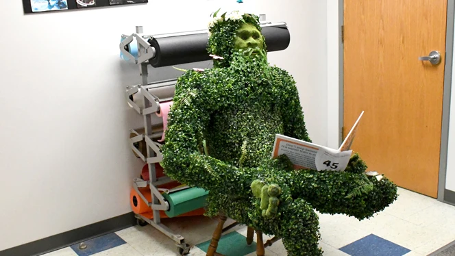 A sasquatch made of plants reading a magazine. A sasquatch made of plants reading a magazine.
