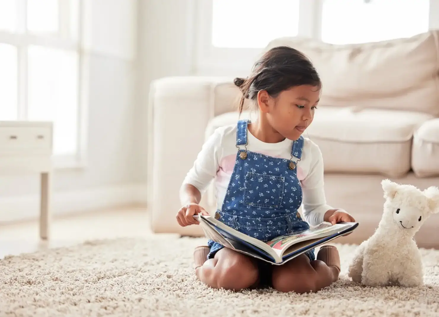 Young girl reading to stuffed animal.