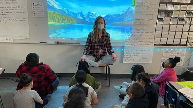 Teacher leading students in breathing exercises.