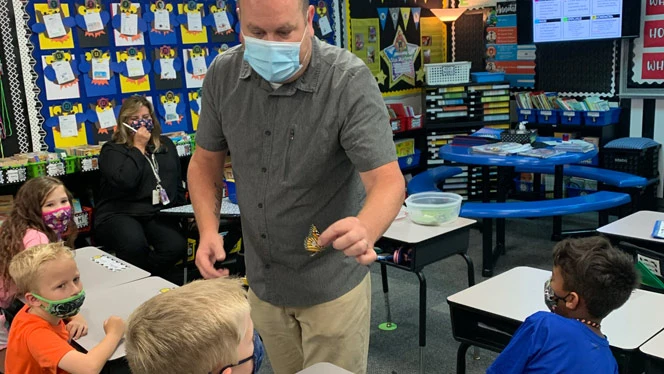 Man showing students a butterfly.