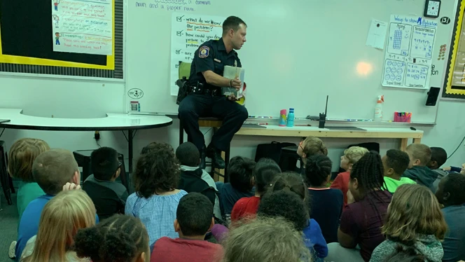 Police officer reading to class.