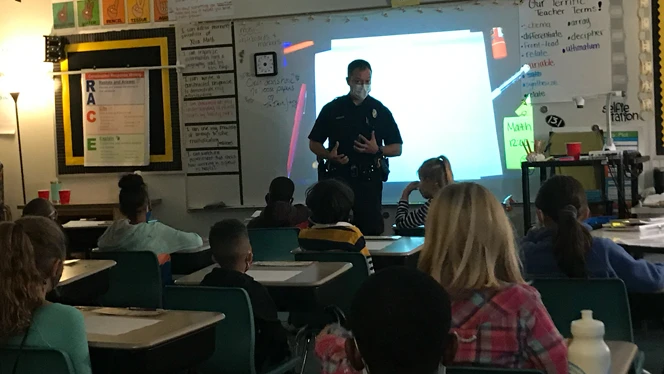 Police officer talking to class.
