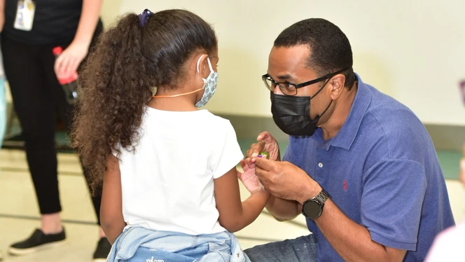 A man handing an object to a child. A man handing an object to a child.