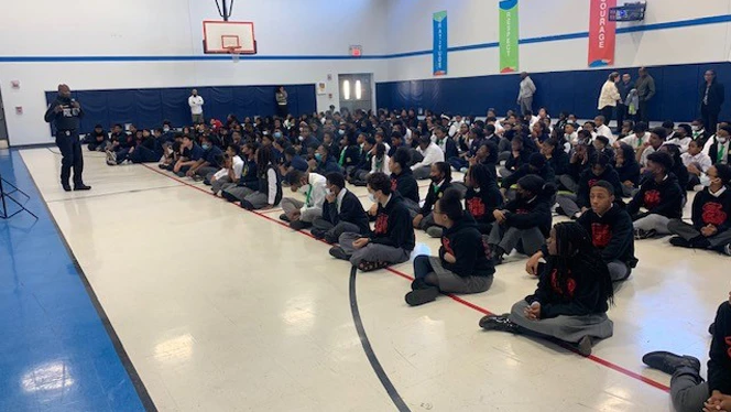 A police officer addresses group of students