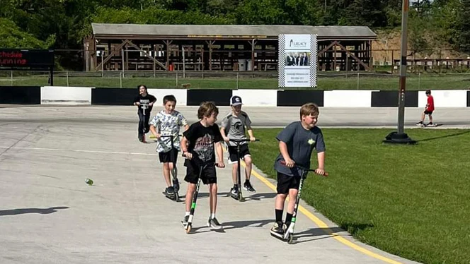 Racers having a little fun racing around the track under their own power on scooters. Racers having a little fun racing around the track under their own power on scooters.