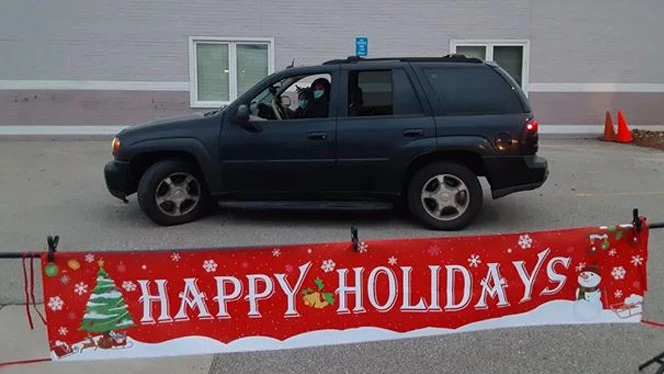 A vehicle in front of a poster that reads Happy Holidays. A vehicle in front of a poster that reads Happy Holidays.