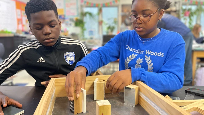 2 students practice setting up their project for event