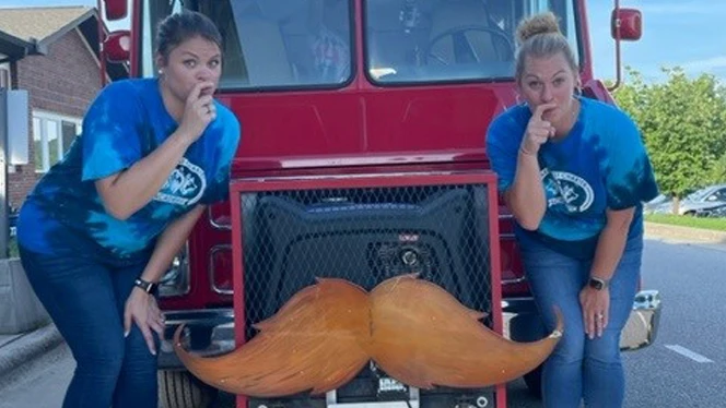 Adults standing next to an ice cream truck. Adults standing next to an ice cream truck.