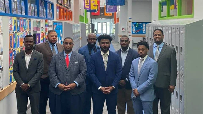 Dr Landon Brown wearing a suit with others. Dr Landon Brown wearing a suit with others.