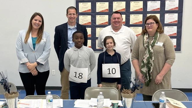 Spelling bee judges standing next to the winners. Spelling bee judges standing next to the winners.