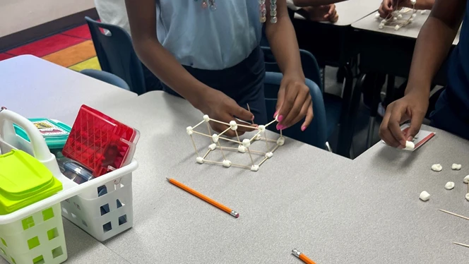 Students building wide structure.