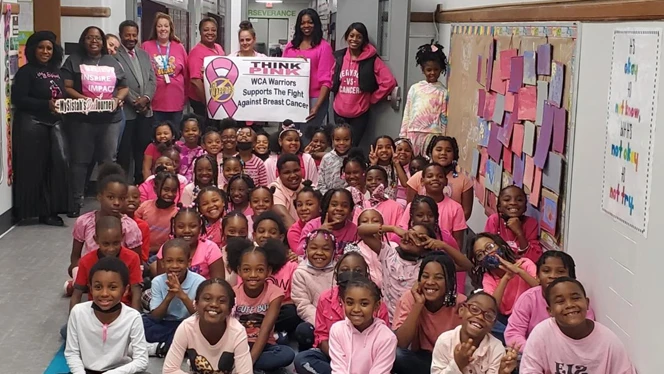 A class wearing pink shirts smiling. A class wearing pink shirts smiling.