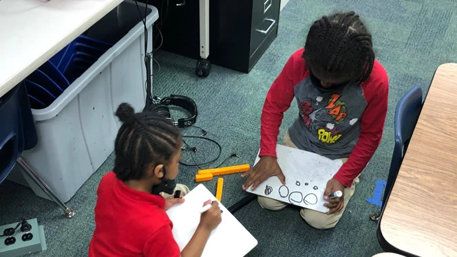 Children kneeling writing on whiteboards. Children kneeling writing on whiteboards.