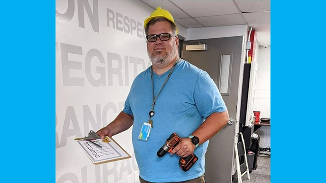 A man holding a power drill. A man holding a power drill.