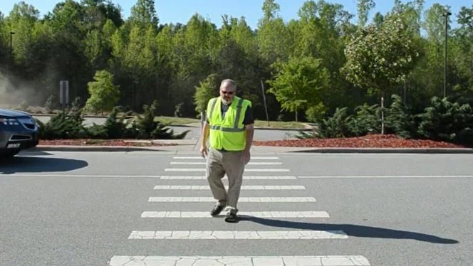 Swofford crossing the street in a safety vest. Swofford crossing the street in a safety vest.