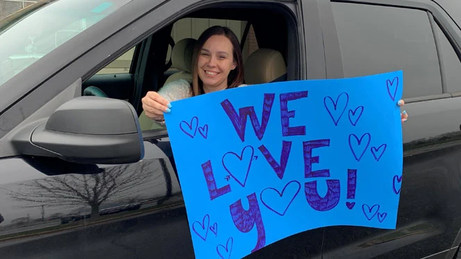 Milwaukee teacher holding we love you sign