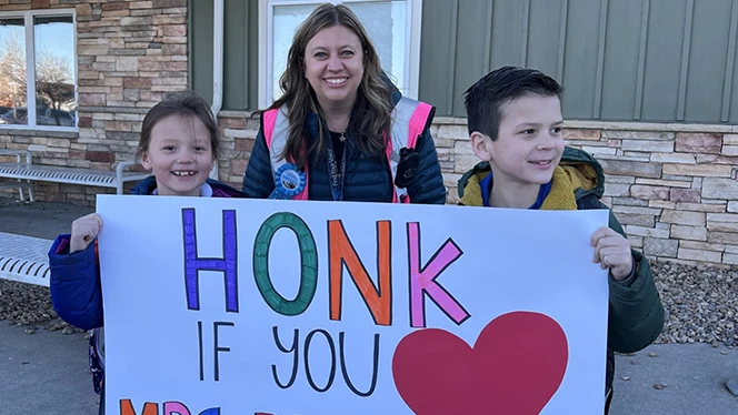 K-8 School in Commerce City: Principal Jenna Reeves stands with Landmark Academy students holding a "Honk If You Love Mrs. Reeves" sign.