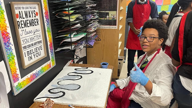 Student painting a ceiling tile