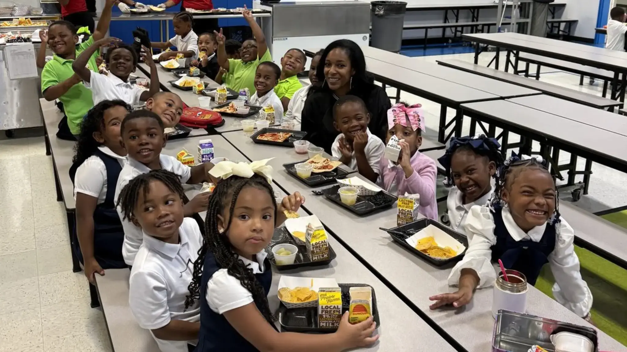 a group of children sitting at a table with a woman and a teacher