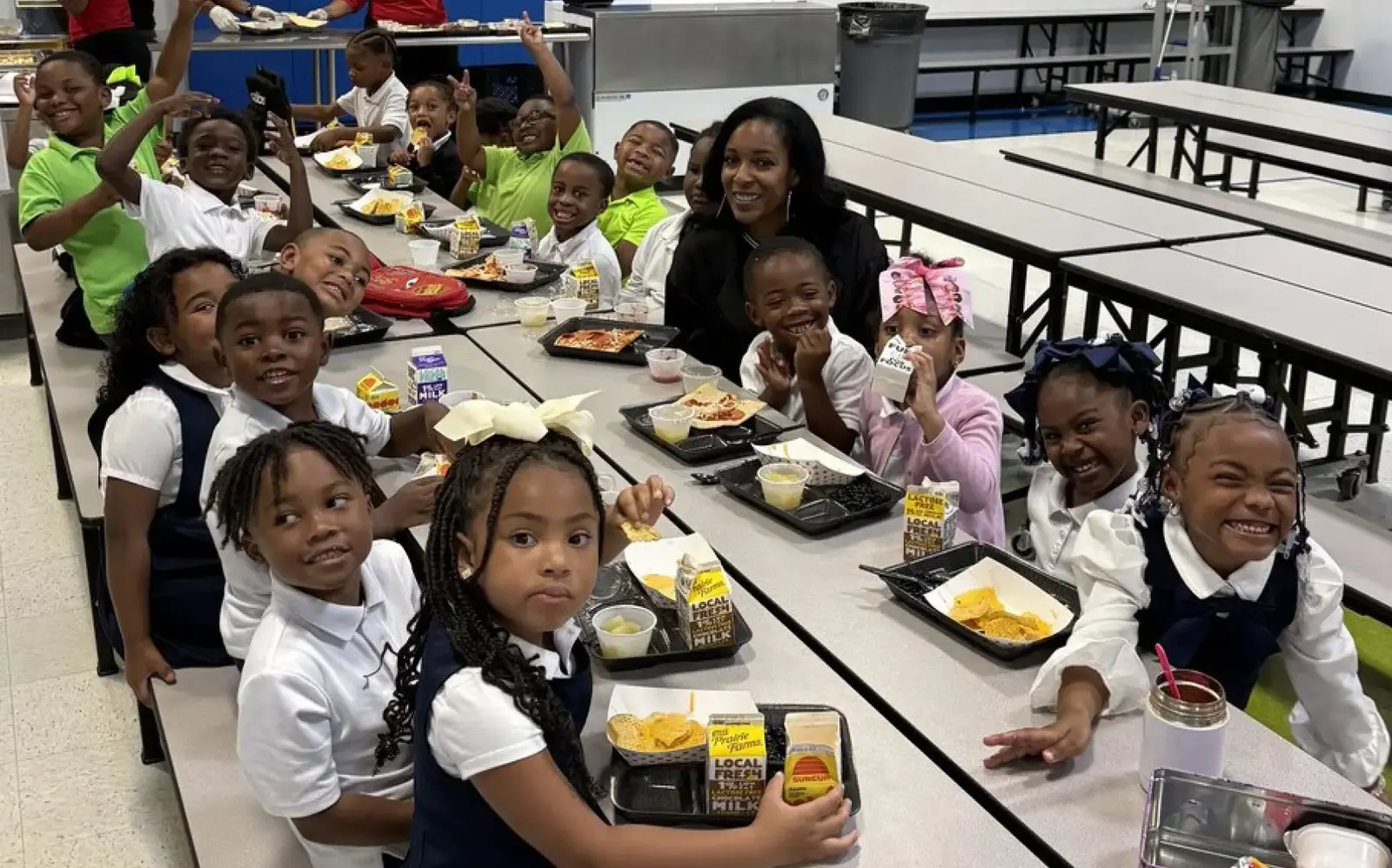 a group of children sitting at a table with a woman and a teacher