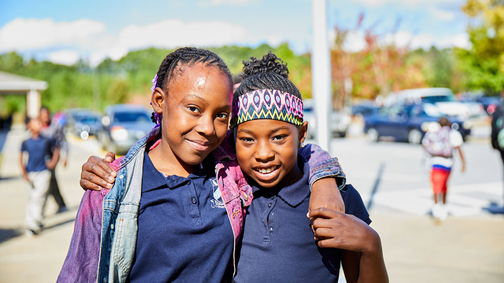Two students smiling in front of their classroom lockers
