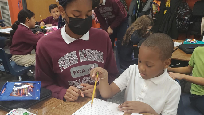 Student helping other student write letter