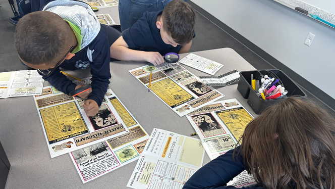 Students using magnifying glasses on articles.