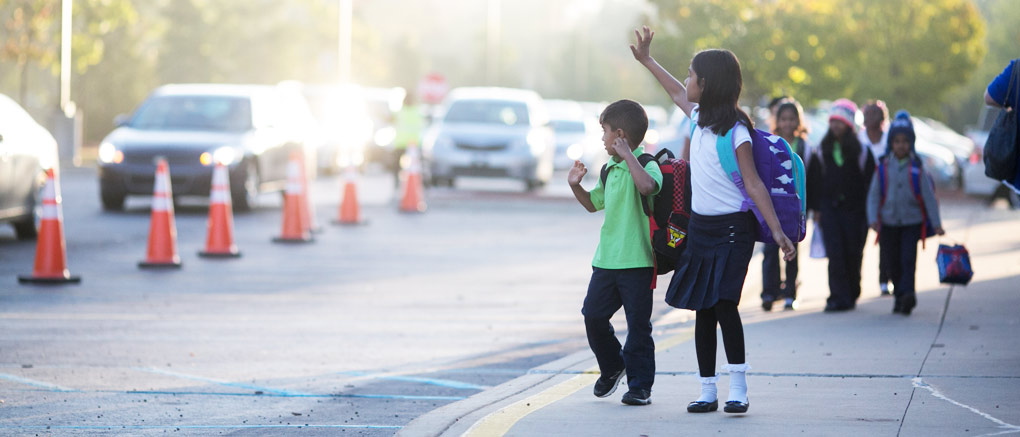 A Teacher Helps a Student Into a Car