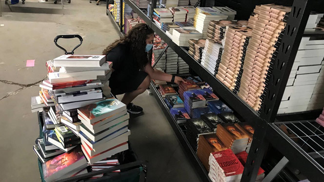 Woman selecting books and loading them onto a cart