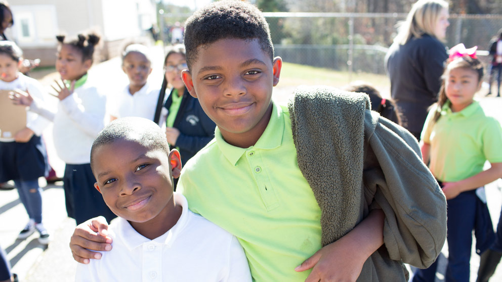 Two students smiling in front of their classroom lockers
