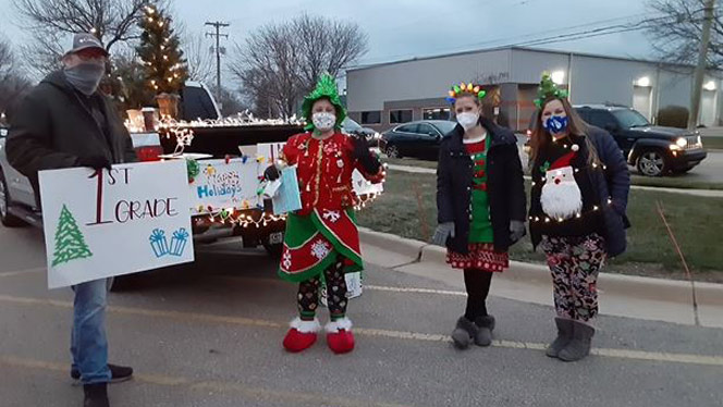 Teachers dressed up in front of a truck with Christmas lights on it.