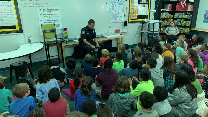 Police officer reading to class.