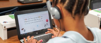 K-8 School in Cincinnati: Student wearing head phones working on laptop.