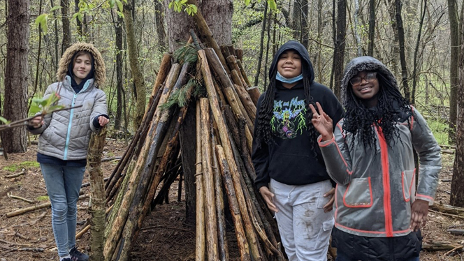 Students posing next to a shelter they made.