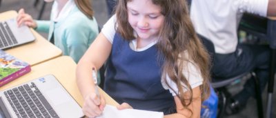 K-8 School in Ypsilanti: Student working on worksheet, using laptop.