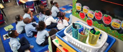 K-8 School in Cincinnati: Class room supplies with students sitting in group on the floor in background.