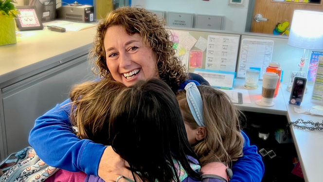 Christina Hasselkus smiling and hugging her students