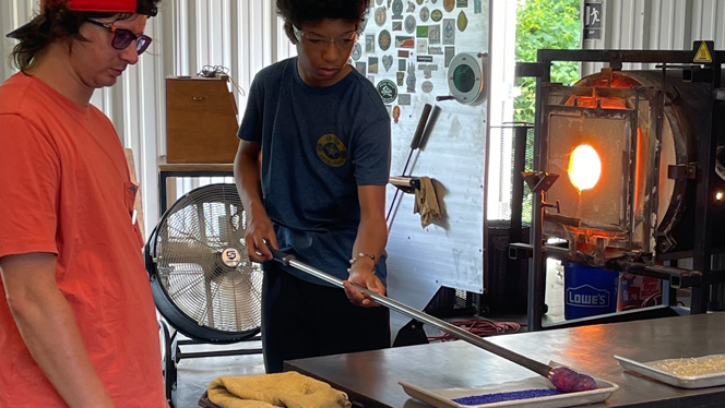 A student applying the color to the glass.