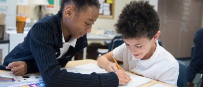 Two students help each other complete work