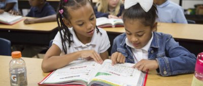 K-8 School in Toledo: Two students reading a textbook together at their desk.