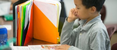 K-8 School in Canton: Student reading book at desk.