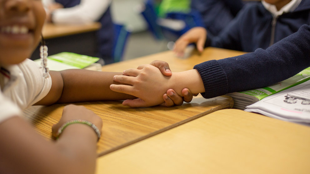 Two students smiling in front of their classroom lockers