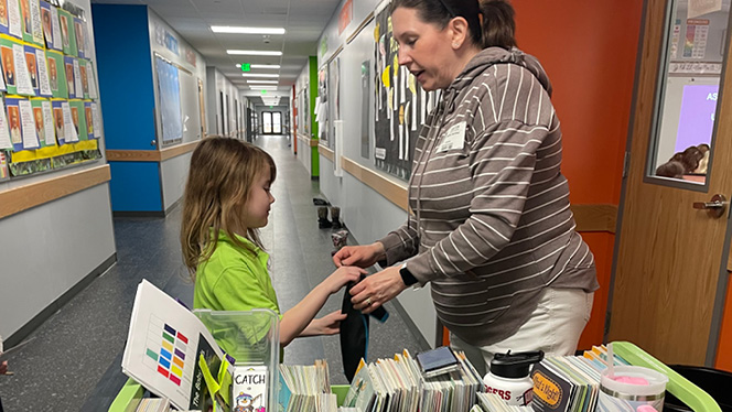 K-8 School in Waukesha: Second-grade scholar Nova Rogers exchanges her book as a part of Mill Creek’s Book in a Bag program.