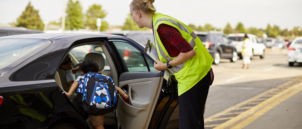 Teacher helping student into car