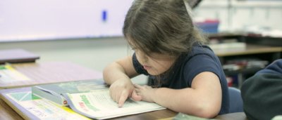 Burton Glen Charter Academy, Y5-8 School in Burton, MI: little girl using her finger to keep her place in a book.