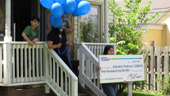 Alondra Pedroza holding up her scholarship in front of her house..