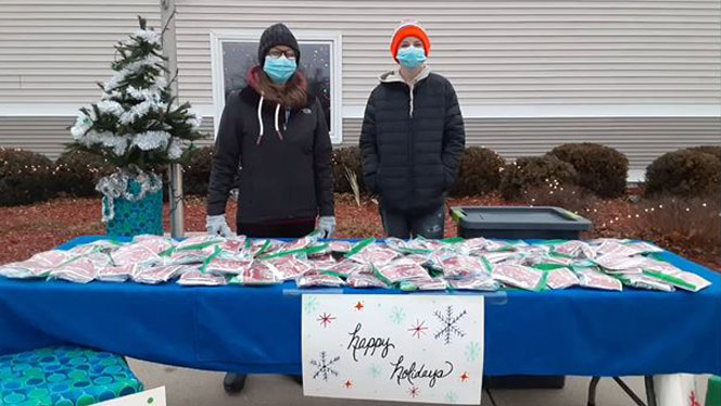 Adults standing in the cold at a gift table.