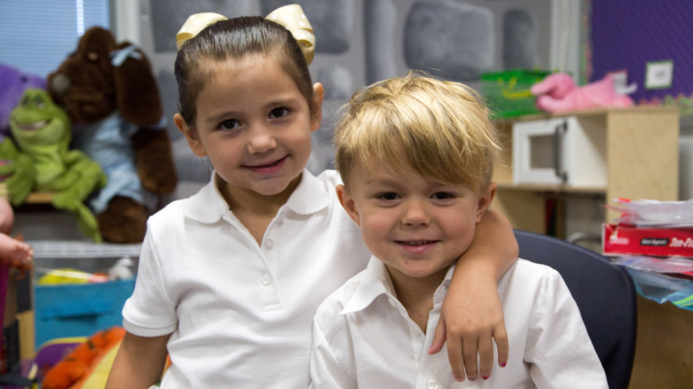 Two students smiling in front of their classroom lockers