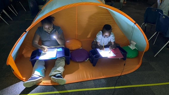 students in a tent reading a book