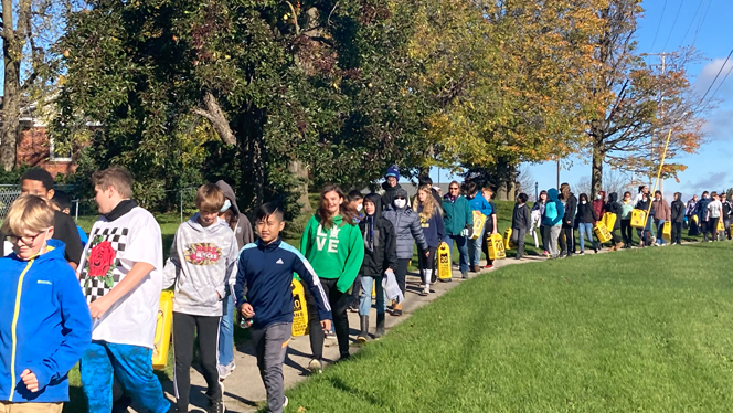 Students in a line carrying water.